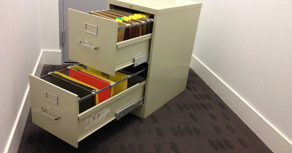 Beige two-drawer steel file cabinet with both drawers pulled open, showing hanging folders inside